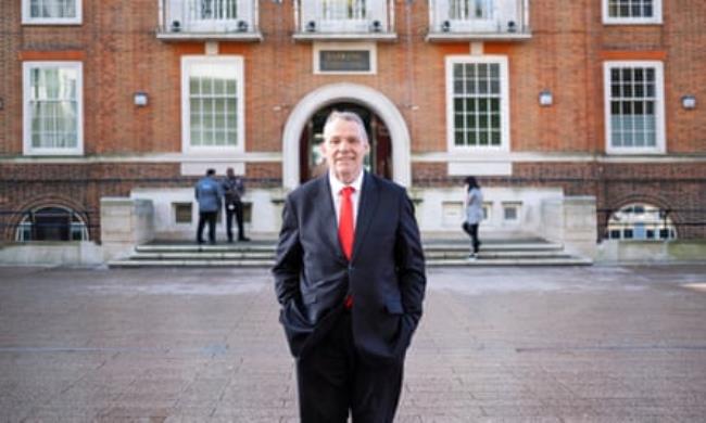 Darren Rodwell stands smiling in a suit in front of the impressive facade of town hall