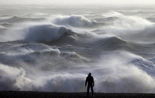 TOPSHOT - A person looks out towards the waves crashing on the shore in Newhaven on January 2, 2024, as Storm Henk was set to bring strong winds and heavy rain across much of southern England. (Photo by ADRIAN DENNIS / AFP) (Photo by ADRIAN DENNIS/AFP via Getty Images)