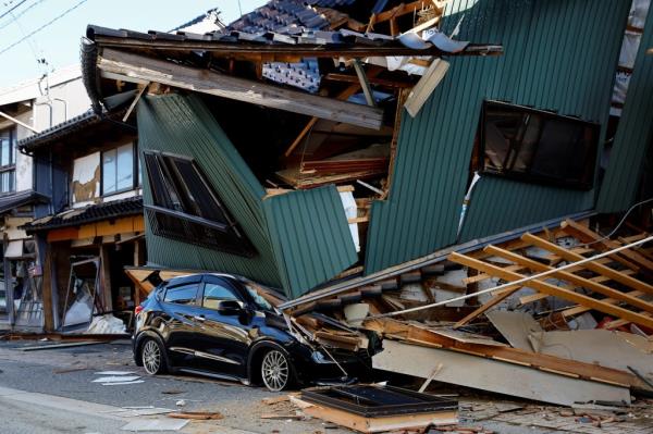 A damaged car stands near a collapsed house, following an earthquake, in Nanao, Ishikawa prefecture, Japan January 2, 2024.