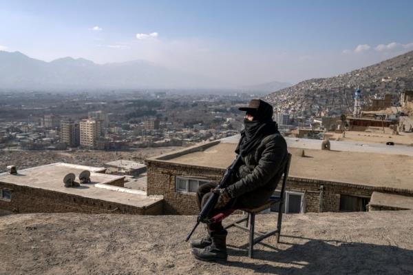 A Taliban fighter sits as he watches the area in Kabul, Afghanistan