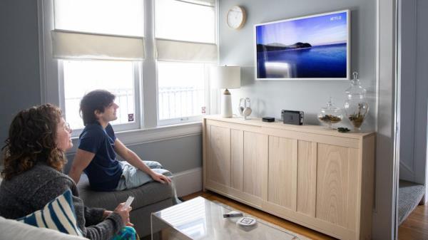 Man and woman sitting on a couch watching a Samsung f<em></em>rame TV