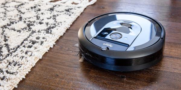 Robotic vacuum on hardwood floor next to area rug