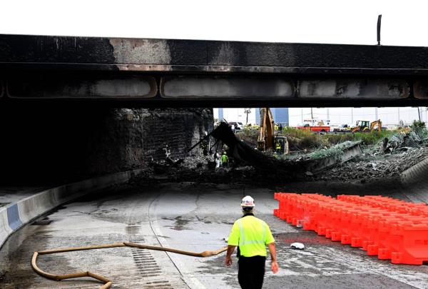 Workers inspect and clear debris from a section of the bridge that collapsed on Interstate 95 after an oil tanker explosion on June 12, 2023 in Philadelphia, Pennsylvania.  Traffic was severely affected due to the closure of this primary north-to-south highway for East Coast travel.