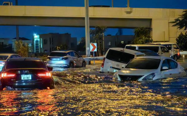 Cars drive in a flooded street following heavy rains in Dubai on April 17, 2024. Dubai, the Middle East's financial centre, has been paralysed by the torrential rain that caused floods across the UAE and Bahrain and left 18 dead in Oman on April 14 and 15. (Photo by Giuseppe CACACE / AFP)