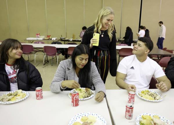 Hope Vaughn, second from right, talks with Manuel Goitia during a potluck Thanksgiving dinner at St. Agatha Catholic Church in Chicago on Nov. 21, 2023. Vaughn was one of the organizers who made traditio<em></em>nal Thanksgiving dinner foods to share with migrants.