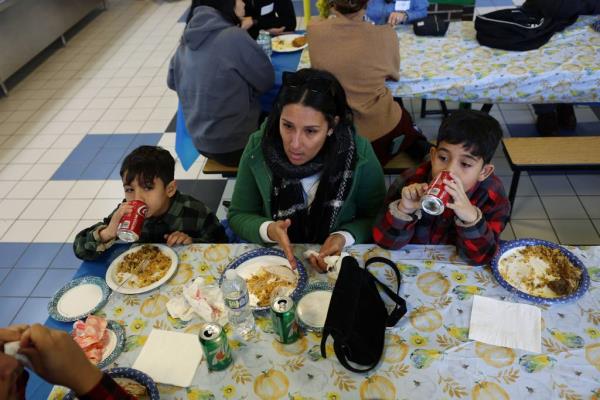 Marienny Brito sits with her children Paul, 6, left, and Juan Pablo, 9, as they take part in a potluck Thanksgiving dinner with students, teachers and parents at Chappell Elementary School in Chicago on Nov. 22, 2023. The Venezuelan migrant family is staying at a nearby shelter while Paul and Juan Pablo attend Chappell. 