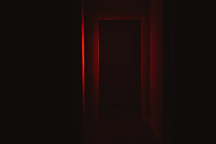 Stock image of door illuminated in red light in haunted house.