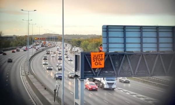 A Just Stop Oil activist on an overhead gantry on the M25, 9 November 2022.