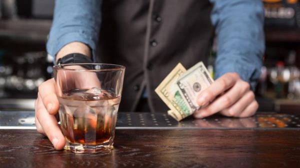 Barman giving whiskey glass with booze - closeup.