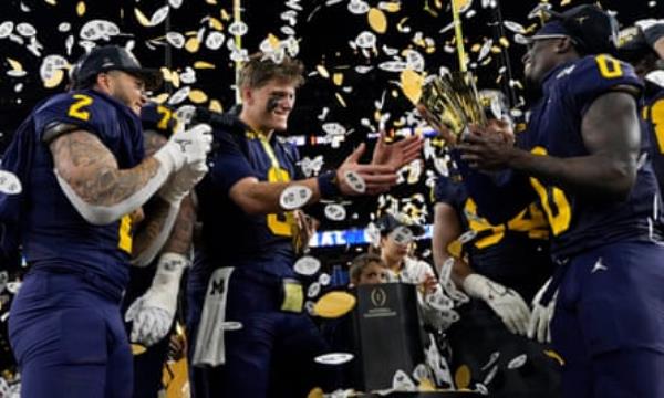 Michigan quarterback JJ McCarthy celebrates with trophy and team mates