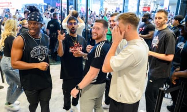 A group of young men pointing, smiling and talking in the middle of a busy shopping centre