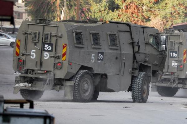 Israeli military vehicles move through a street after Israeli forces raided the Jenin refugee camp in the Israeli-occupied West Bank, November 17, 2023. REUTERS/Raneen Sawafta