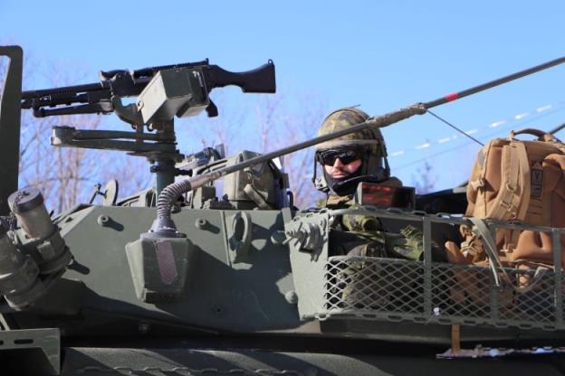 A man wearing military uniform sits in a light armoured vehicle 