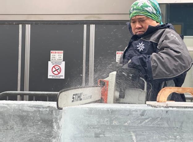 A man uses a chain saw to cut ice for a sculpture 