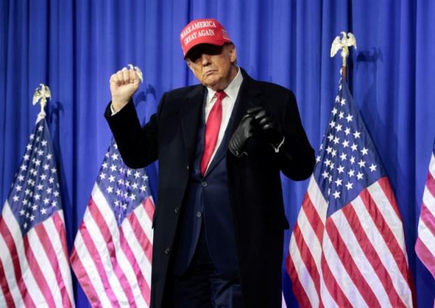 Do<em></em>nald Trump in a long, black coat and wearing a red 