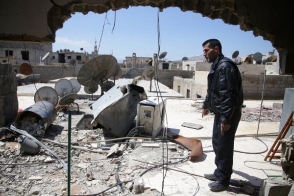 Abu Ghassan, 50, one of the survivors of a chemical attack in the Ghouta region of Damascus that took place in 2013, points at a piece of one of the rockets fired in 2013, as he stands in the Ghouta town of Ain Tarma, Syria April 7, 2017. Picture taken April 7, 2017. REUTERS/Bassam Khabieh