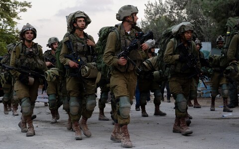 Israel Defense Forces soldiers walk through Kibbutz Be'eri wher<em></em>e days earlier Hamas militants killed over a hundred civilians near the border with Gaza