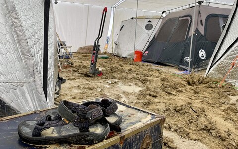 A pair of Teva sandals is seen on a chest in the middle of tents in the muddy desert plains of Burning Man