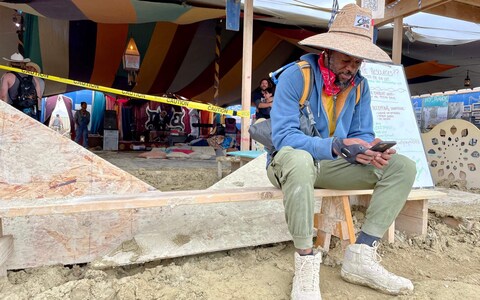 Willo<em></em>nius Hatcher, 39, comedian, screenwriter and AI co<em></em>ntent creator checks his phone at Black Rock City