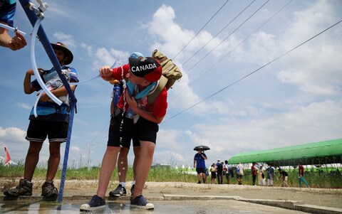 A scout drinks water at a water supply zone of the camping site