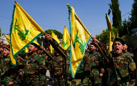 Hezbollah members fly the group’s flag and shout slogans at a funeral in Majadel village, south Lebanon