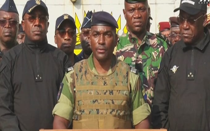 This video grab taken from a video obtained by AFPTV from Gabon 24 on August 30, 2023 shows Colo<em></em>nel Ulrich Manfoumbi Manfoumbi (C), spokesperson of the Committee for the Transition and Restoration of Institutions (CTRI), reading a statement on television