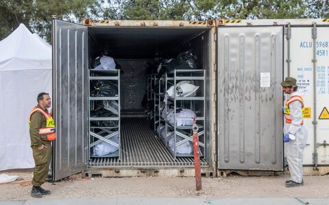 Co<em></em>ntainers store hundreds of black and white body bags that are stacked on me<em></em>tal racks