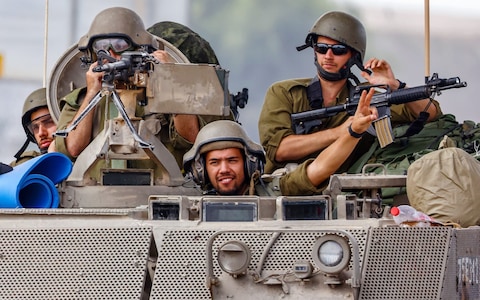 Israeli soldiers drive with an armoured perso<em></em>nnel carrier (APC) and greet fellow soldiers on patrol near the border with Gaza