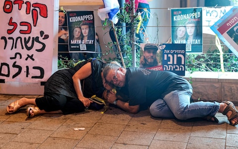 People who were attending a demo<em></em>nstration calling for the release of hostages held by Palestinian militants since the October 7 attack, take cover as warning sirens sound of an incoming rocket attack in Tel Aviv 