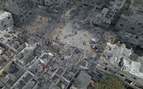 Palestinians walk a<em></em>bout buildings destroyed in the Israeli bombardment in the Nusseirat refugee camp in the Gaza Strip