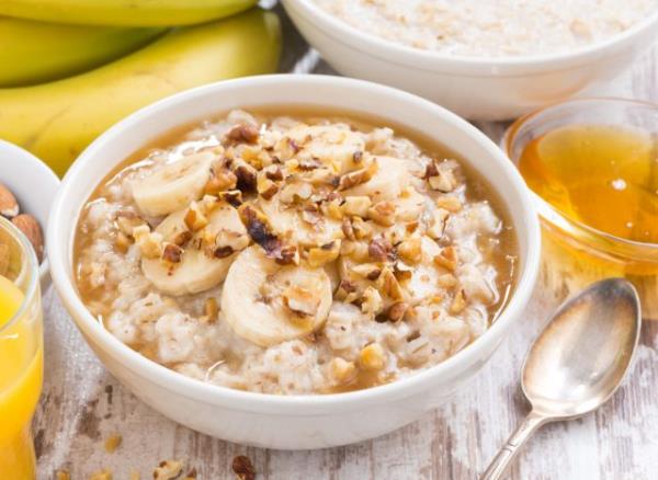 large bowl of oatmeal with bananas and honey, co<em></em>ncept of surprising breakfast foods that can destroy your waistline