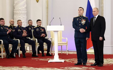 Vladimir Putin presents a medal to a Russian soldier during the ceremony in the Kremlin