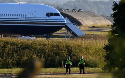 Two police officers near to wher<em></em>e a Boeing 767 sits on the runway at the military ba<em></em>se in Amesbury, Salisbury preparing to take asylum seekers to Rwanda in June, 2022