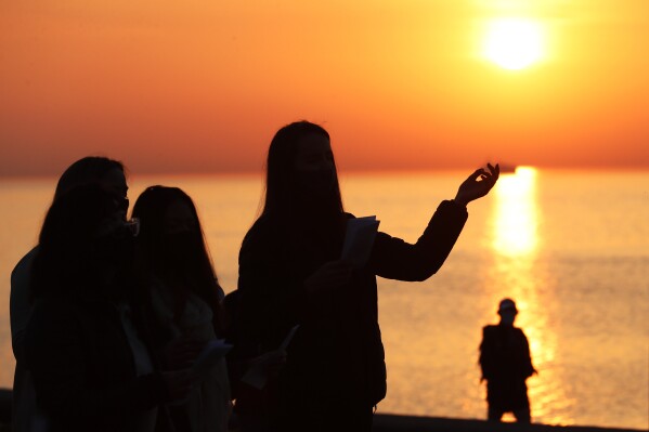 FILE - A parishio<em></em>ner is silhouetted against the rising sun as she prays during an Easter sunrise service held by Park Community Church Sunday, April 4, 2021, at North Avenue Beach in Chicago. On Easter morning, many Christians wake before dawn. They will celebrate their belief in the resurrection of Jesus, the son of God, as the sun rises. (AP Photo/Shafkat Anowar, File)