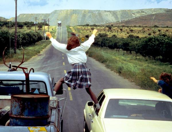 Lori Singer standing between two cars in a scene from 'Footloose'