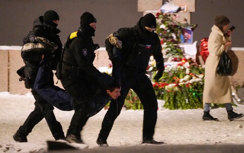 Police officers detain a man laying flowers to Alexei Navalny at the Memorial to Victims of Political Repression in St. Petersburg, Russia on Friday, Feb. 16, 2024. 