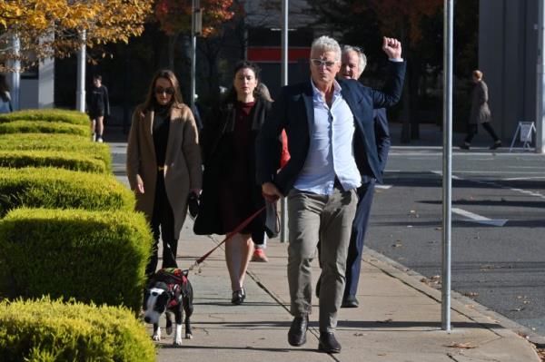 a man raises his fist as he walks with a dog