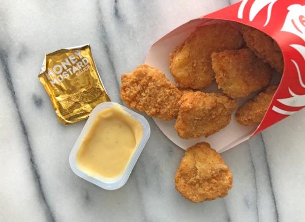 wendy's ho<em></em>ney mustard dipping sauce with nuggets spilled out on a table.