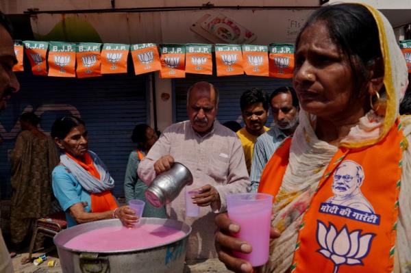 Supporters of India's ruling Bharatiya Janata Party (BJP) distribute sweet drinks outside a polling station during polls on a hot summer day in Karnal, in the northern state of Haryana, India, May 25, 2024.