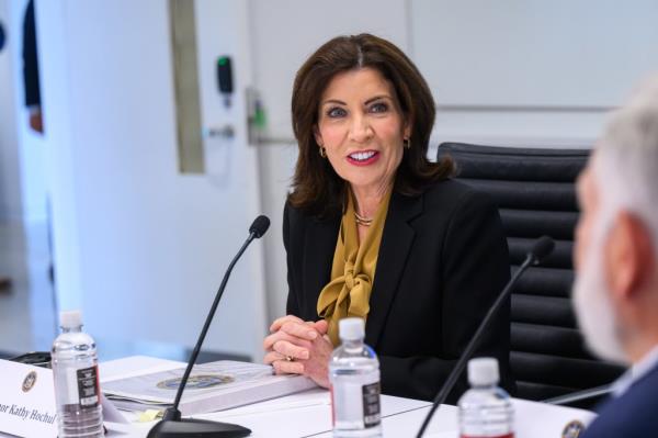 Governor Kathy Hochul sitting at a table with a microphone, discussing the establishment of Empire AI with industry leaders and advocates in New York, NY