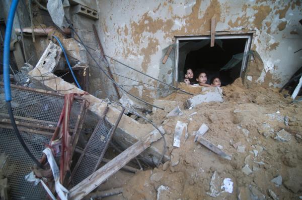 Palestinian children look at a building destroyed in an airstrike.