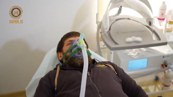 Chechan warlord Razman Kadyrov lies on a stretcher with an oxygen mask over his face.