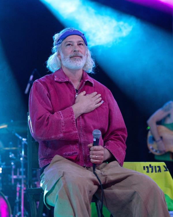 Matisyahu performing with a microphone and his hand on his chest in front of a crowd at Stubb's Waller Creek Amphitheater in Austin, Texas.