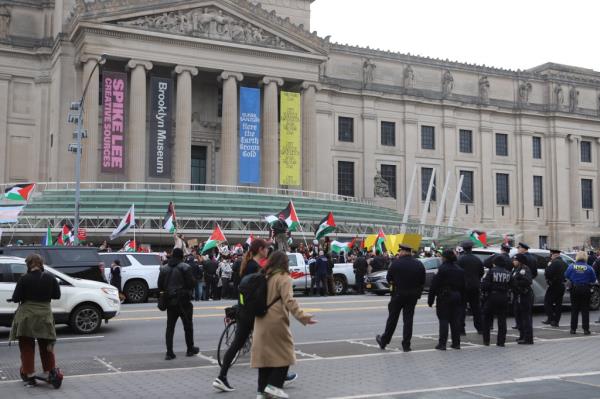 Protesters holding flags and signs outside the Brooklyn Museum. 