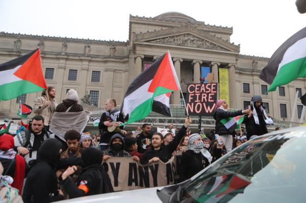 Protesters holding flags and signs outside the Brooklyn Museum. 