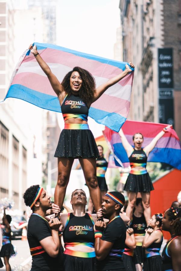 A cheerleader waves a multicolored flag over her head.