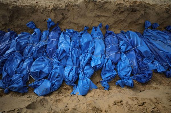 Bodies of people killed in Israeli airstrikes being buried in a mass grave in Khan Younis on Wednesday