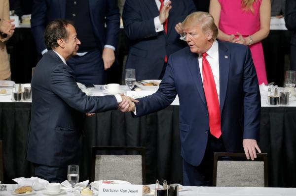 President Do<em></em>nald Trump, right, shakes hands with John Paulson