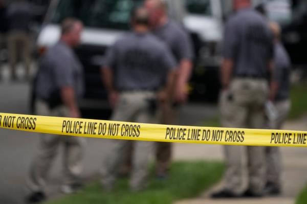 Police line at a house with police in the background. 