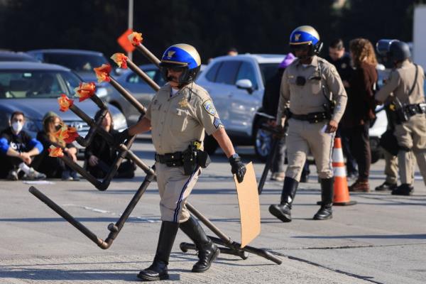 An officer carrying a large menorah off the highway. 